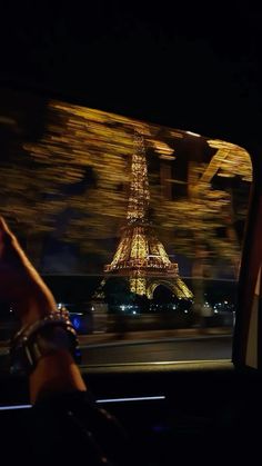 the eiffel tower is lit up at night as seen from inside a car