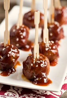 mini meatballs covered in sauce and toothpicks on a white plate with chopsticks