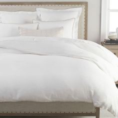 a bed with white sheets and pillows in a bedroom