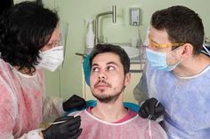 three people wearing masks and gowns in a room