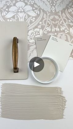 some paint samples and a brush sitting on top of a white table with silver wallpaper