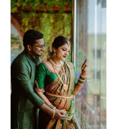 a man and woman standing next to each other in front of a window