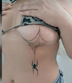 a woman's back with a spider tattoo on her ribs and the bottom part of her stomach