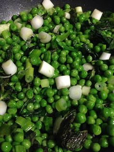 peas and onions are being cooked in a wok