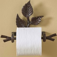 a toilet paper holder with two leaves on it and a towel roll hanging from the wall