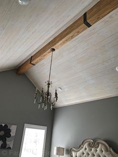 a chandelier hangs from the ceiling in a bedroom with gray walls and white bedding