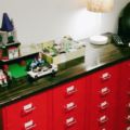 a room with red cabinets and lots of legos on the top one shelf, next to a lamp