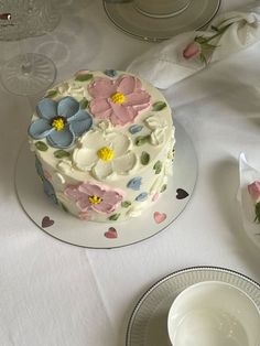 a white table topped with a cake covered in frosting and pink and blue flowers