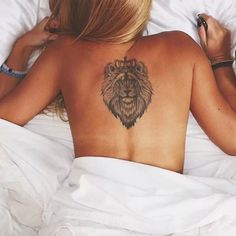 a woman laying in bed with a lion tattoo on her back and the caption instagram