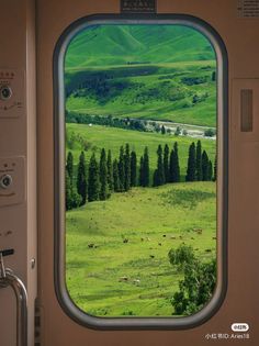 an airplane window with the view of green hills and trees from it's seat