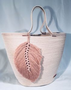 a pink and white bag with tassels hanging from it's handles on a white background