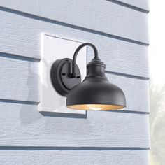 an outdoor light mounted on the side of a wall next to a blue siding building