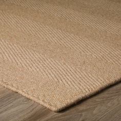 a close up view of a beige rug on a wooden floor with wood grains