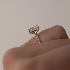 a woman's hand holding an engagement ring with a diamond in the middle, on top of her finger