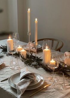 a table set with candles, plates and napkins