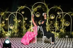 a man and woman sitting on chairs in front of a stage