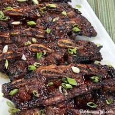 grilled meat on a white platter with green onions