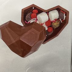 there is a chocolate heart shaped box filled with candy and marshmallows in it