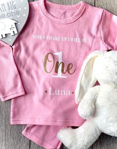 Celebrate your little ones special 1st birthday with our birthday Eve pyjamas. These pink baby girls 'When I Wake Up I Will be One' pyjamas/pjs are beautifully personalised with white and gold glitter detailing. These PJ's are essential for the baby that has everything or as a great idea for someone looking for that personal and individual gift *Also available in blue with white & silver glitter detailing * Our pyjamas are 100% cotton 200gsm (approx) SIZES AVAILABLE: 6-12 months (PJ Top Approx - Height 35cm & Width 29cm / PJ Bottom Approx - Width 21cm & Length 40cm) (from experience these PJ's come up large so 6-12 months normally fits all, but please check measurements) This banner is part of our Birthday Collection ( https://www.etsy.com/shop/teddybearsandbows/?section_id=34821784 ). The Long Sleeve Cotton Set For Birthday, Cotton Long Sleeve Sets For Birthday, Pink Long Sleeve Sets For Birthday, Pink Cotton Sets For Birthday, Pink Birthday Pajamas, Pink Letter Print Sets For Pajama Party, Personalized Cute Sets For First Birthday, Pink Long Sleeve Birthday Set, Birthday Pyjamas