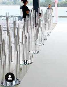 a woman standing next to a row of glass poles