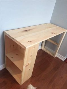 a wooden desk sitting on top of a hard wood floor next to a white wall