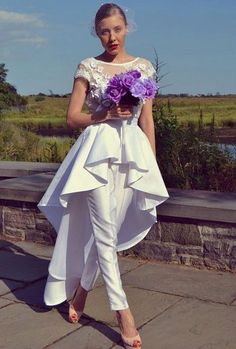 a woman in white is posing for a photo with flowers on her head and dress