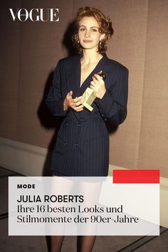 a woman standing in front of a wall with her hands on her hips and holding an award