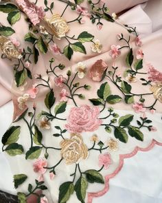 pink and gold flowers on white fabric with green leaves in the center, being held by someone's hand