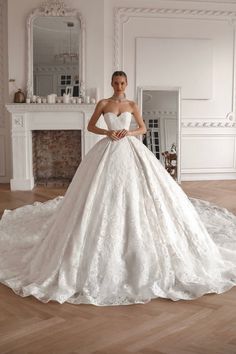 a woman in a white wedding dress standing next to a fireplace with her hands on her hips