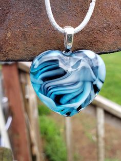 a heart shaped glass pendant hanging from a chain