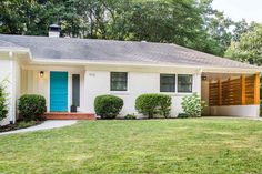 a white house with blue door and green grass in the front yard on a sunny day