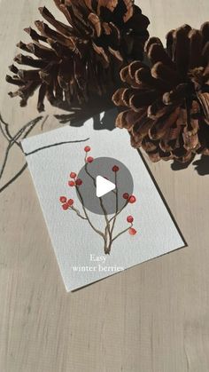 a pine cone sitting on top of a table next to a card with an image of a flower