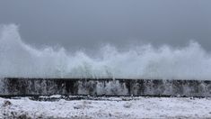 waves crashing against the sea wall on a gloomy day