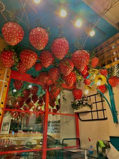 strawberries are hanging from the ceiling in front of a storefront with lights above them