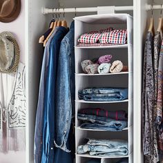 an organized closet with clothes and hats hanging on the wall, including jeans and jackets