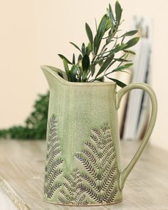 a plant in a green vase sitting on a table