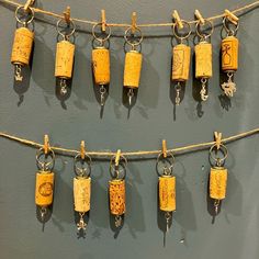 there are many corks hanging on the clothes line with keys attached to them,