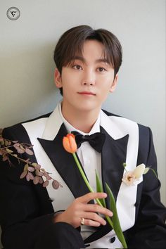 a young man in a tuxedo holding flowers