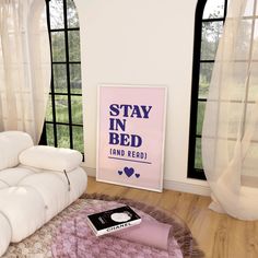 a white couch sitting on top of a hard wood floor next to a pink poster