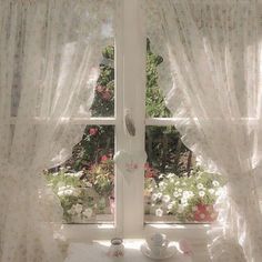 there is a window with white curtains in the room and flowers on the windowsill