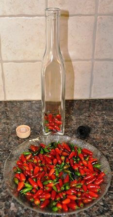 a bowl full of red peppers sitting on top of a counter next to a bottle