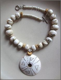 A string of creamy spheres of various shape and size mingle with ostrich egg-shell and milky glass from Africa. Tawny etched beads from Tibet add subtle contrast to the monochrome palette.  Age and wear have contributed to the rich patina of these cherished beads from the Himalayas.  An etched shell disc from Nagaland provides additional global cachet and seals the deal for artistic statement. A handmade silver toggle clasp from Thailand pulls this distinctive one-off design by Deborah Garner to White Artisan Necklace With Wooden Beads, Artisan White Necklace With Wooden Beads, White Bohemian Jewelry With Wooden Beads, Bohemian White Jewelry With Wooden Beads, White Jewelry With Wooden Beads, White Jewelry With Round Wooden Beads, Unique White Round Necklace, Unique White Round Necklaces, Unique Round White Necklaces