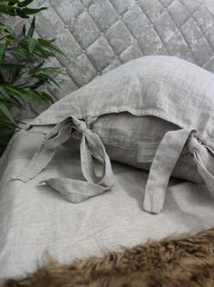 a bed that has some kind of pillow on top of it with a plant in the background