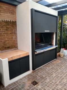 an outdoor kitchen with black cabinets and brick flooring