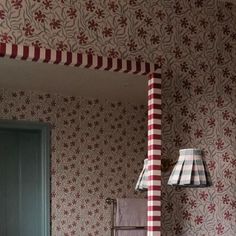 a bathroom with red and white wallpaper, green door and toilet paper roll on the floor