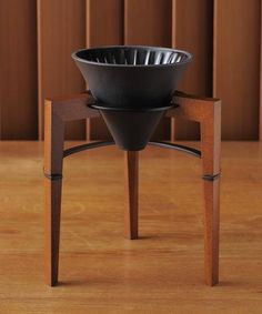 a wooden table topped with a black bowl on top of a metal cupcake stand