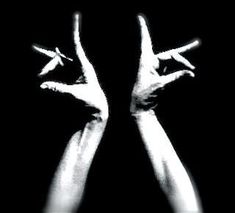 two hands reaching up in the air with their fingers pointing towards each other, against a black background