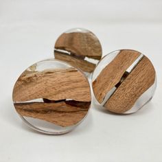 three wood and glass knobs on a white surface with no one around them or in the background