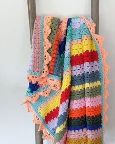 a multicolored crocheted blanket sitting on top of a wooden chair