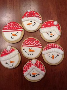 six decorated cookies with hats and snowmen on them sitting on top of a wooden table